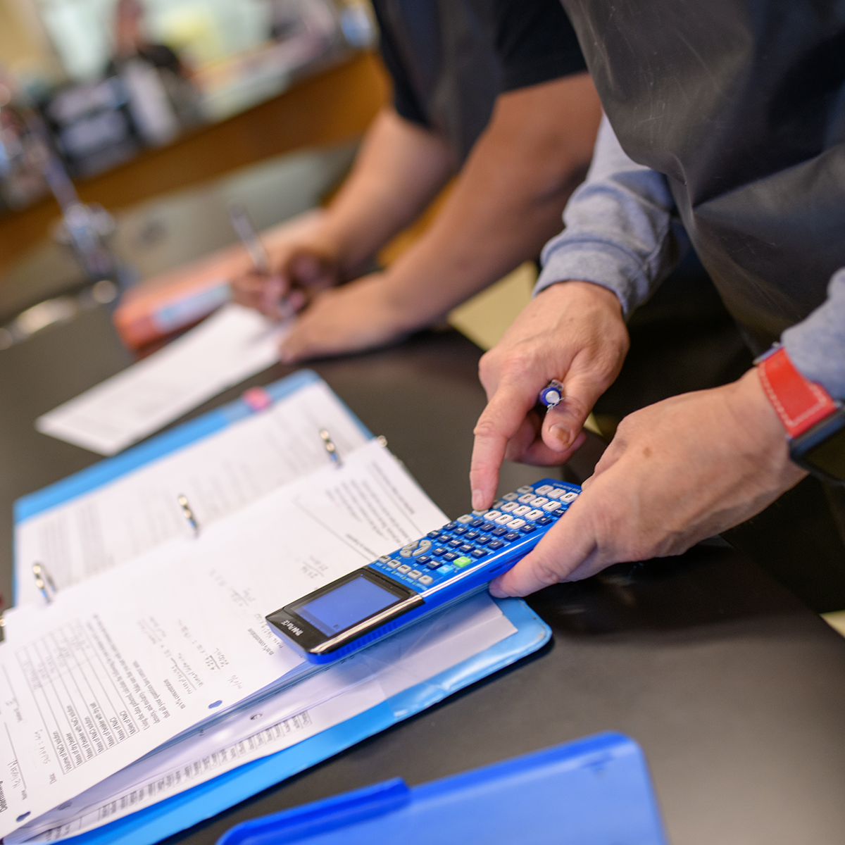 A students hands are visible using a calculator